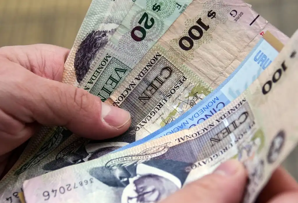 Una persona sostiene billetes uruguayos