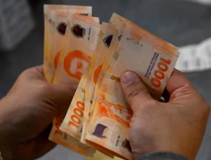 Una persona cuenta billetes de 1000 pesos