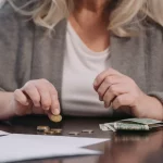 Persona calcula sus deudas con tarjetas de crédito sobre la mesa