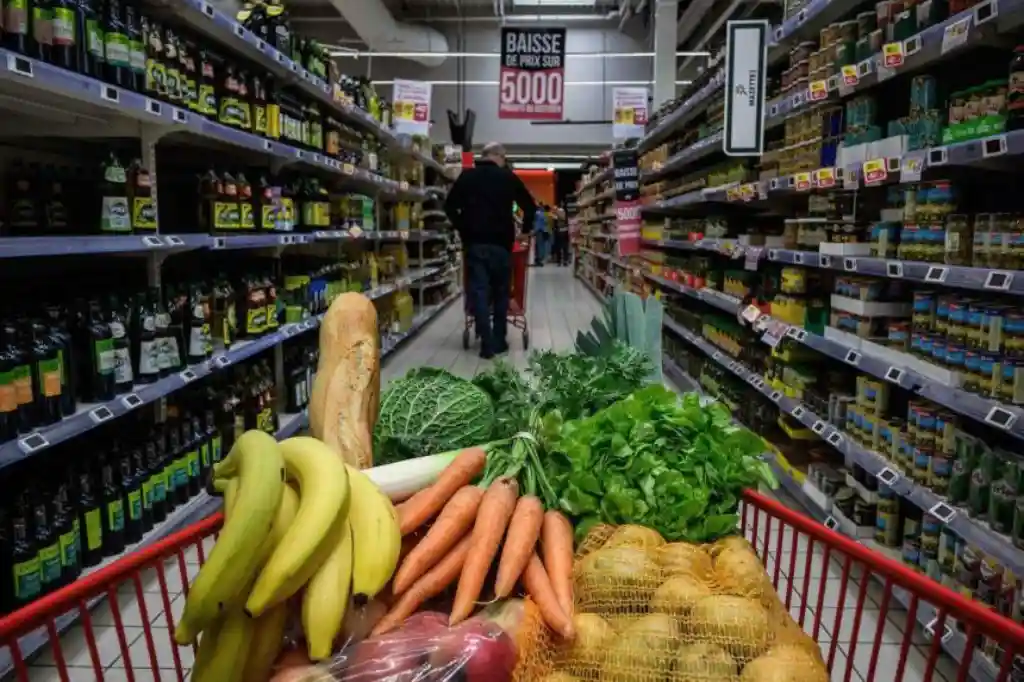 Carrito con frutas y verduras frescas en supermercado mostrando variedad de alimentos básicos
